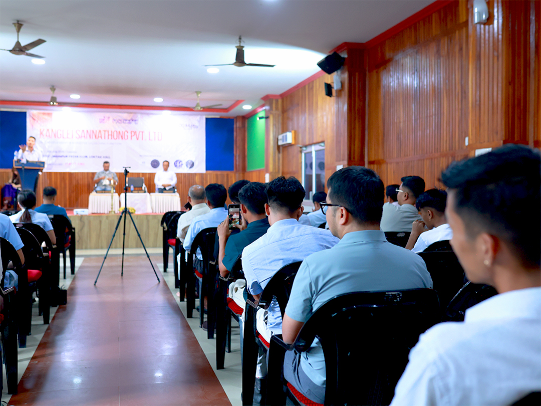A speaker addressing the audience from the stage at a Kanglei Sannathong event in Manipur.