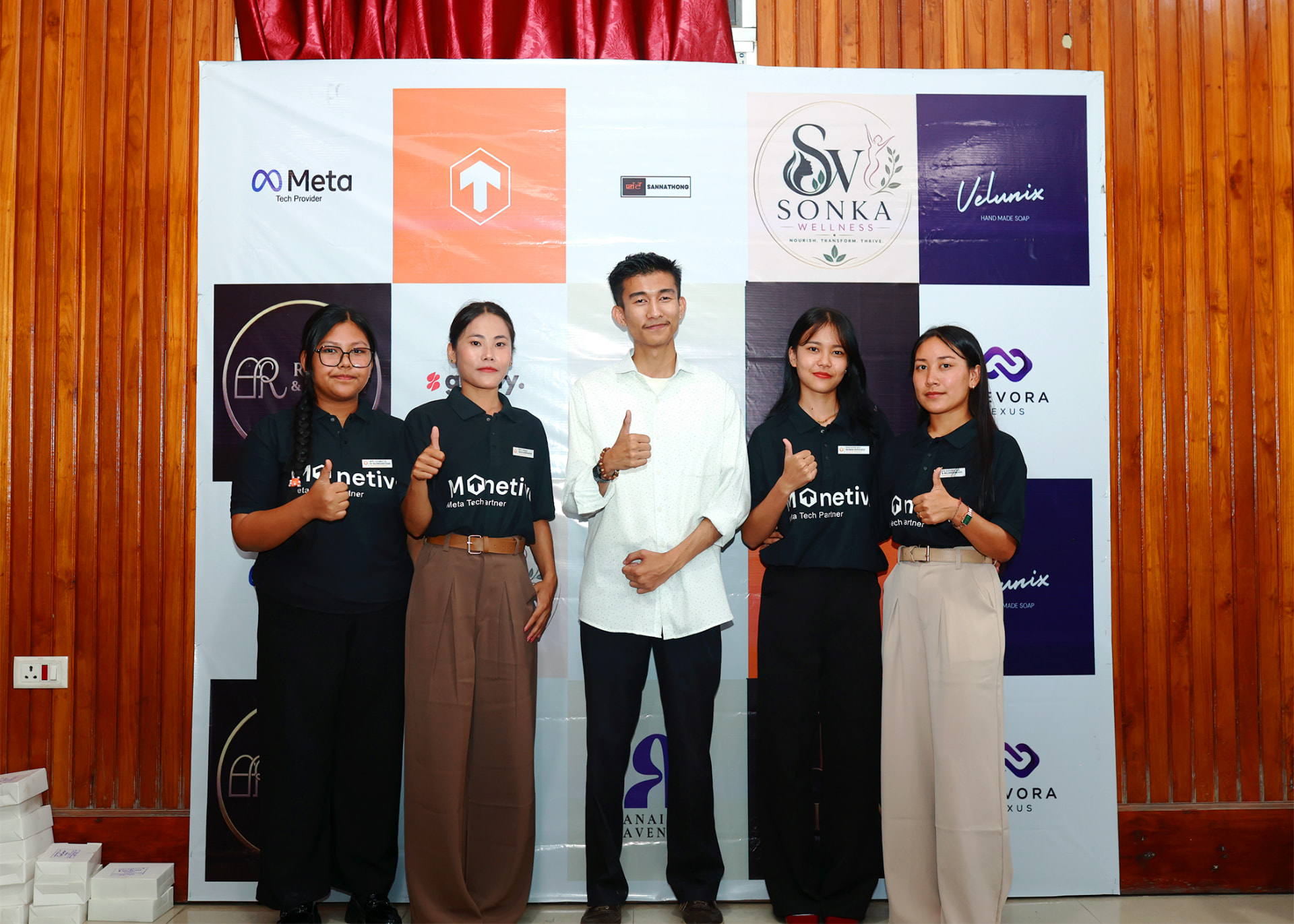 Team and partner members in Monetive Meta Tech Provider shirts posing at a branded backdrop.